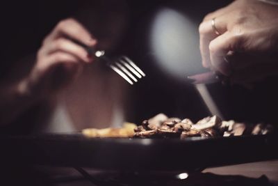 People holding food over plate on table