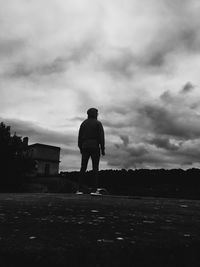 Rear view of silhouette man standing on field against sky