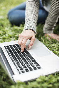 Cropped image of businesswoman using laptop on grass