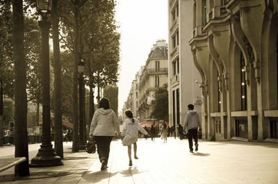 Rear view of people walking on street amidst buildings