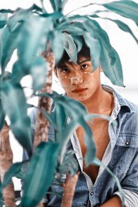 Portrait of young man with plants in foreground