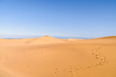 Scenic view of desert against clear blue sky
