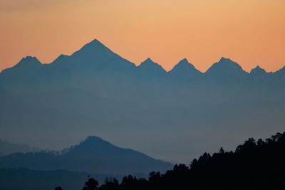 Scenic view of silhouette mountains against orange sky