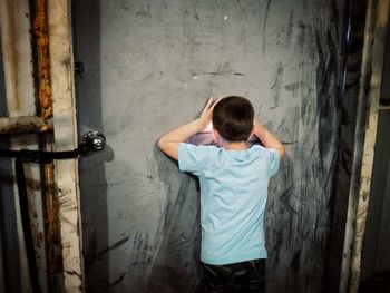 Rear view of boy peeping through door