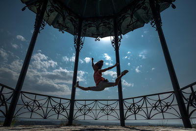 Low angle view of boy jumping against sky