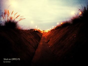 Illuminated road against sky at night