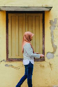 Full length of woman standing against building