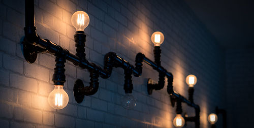 Low angle view of illuminated light bulbs hanging on street