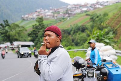 Portrait of young man smoking cigarette on road