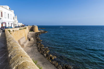 Scenic view of sea by buildings against clear blue sky