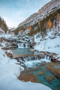 Frozen lake by snowcapped mountain against sky