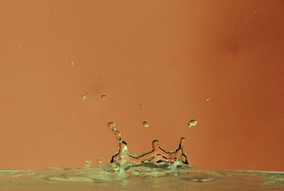 Close-up of splashing water against orange background