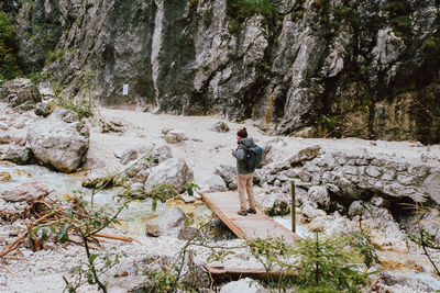 Rear view of woman standing on rock against trees