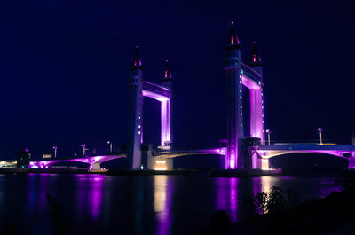 Illuminated bridge over river at night