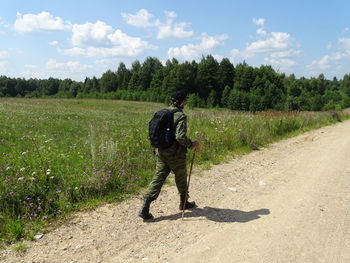 Rear view of man standing on field against sky