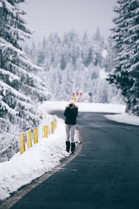 Woman photographing on road during winter