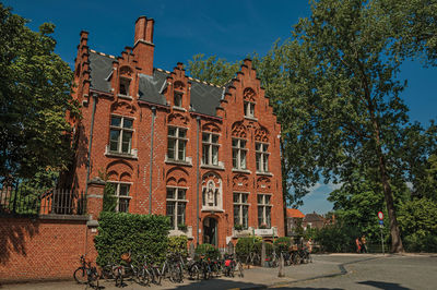 Brick facade of old house, trees and bicycles in bruges. a town full of canals in belgium.