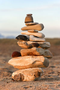 Stack of stones on field against sky