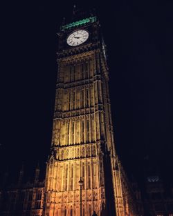 Low angle view of clock tower at night