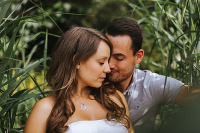 Husband and wife sitting against plants