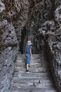 A boy standing on the stone stairs in a through grotto located in the rock