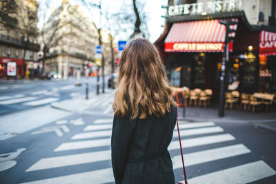 Rear view of woman standing on street in city