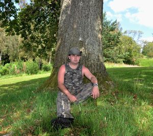 Portrait of smiling boy on tree trunk against sky