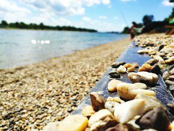 Close-up of pebbles on beach against sky