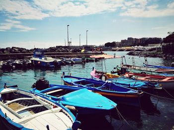 Boats moored at harbor against sky