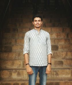 Portrait of young man standing against wall