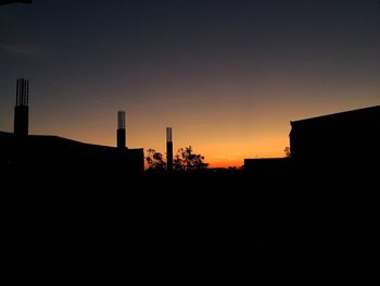 Silhouette of factory against clear sky