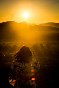 Rear view of man on mountain against sky during sunset