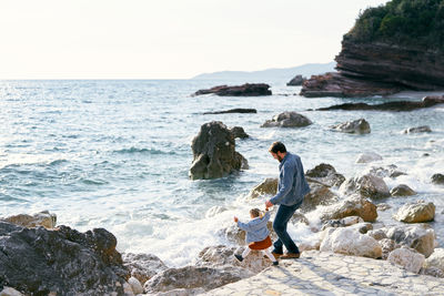 Rear view of two people looking at sea against sky