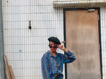 Young woman wearing sunglasses standing against closed door