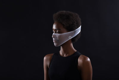 Portrait of young man standing against black background