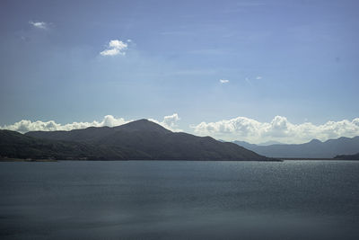 Scenic view of lake by mountains against sky