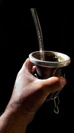 Close-up of hand holding drink against black background