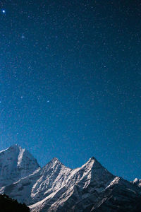 Low angle view of snowcapped mountain against blue sky