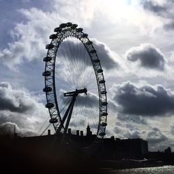 Low angle view of ferris wheel against cloudy sky