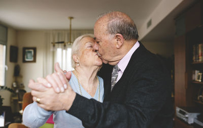 Senior couple kissing and dancing at home