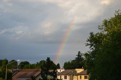 Low angle view of rainbow over houses against sky