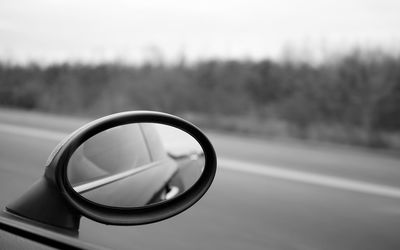 Black and white picture of an outer rear mirror driving along a field