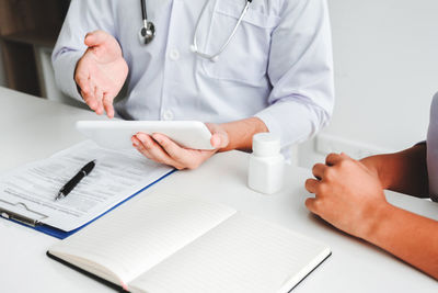 Midsection of man reading book on table