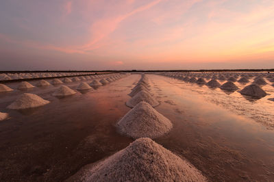 Salts at beach against sky at sunset