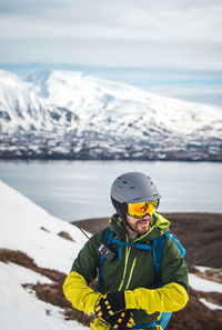 Man adjusting his glove skiing in iceland with water behind him