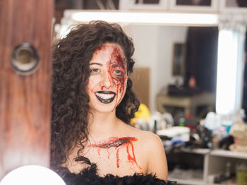 Close-up of young woman with spooky face paint reflecting on mirror