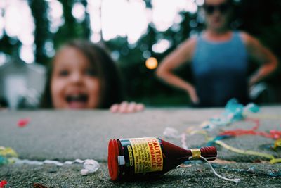 Close-up of firework in bottle on retaining wall with people in background