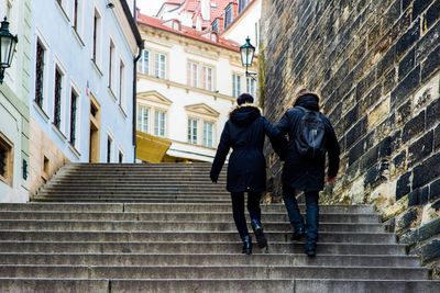 Rear view of people walking on stairs in city