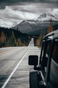 Road leading towards mountains seen through car window