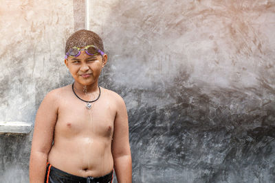 Portrait of smiling boy standing against wall